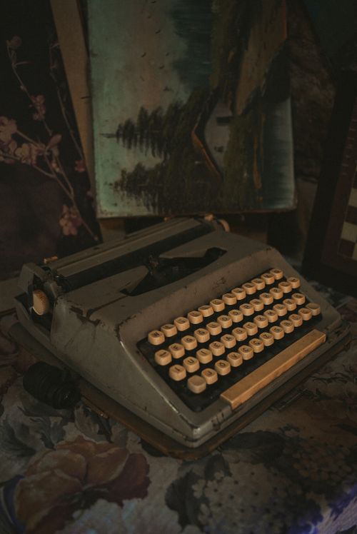 Free Old typewriter with a vintage feel against a creative backdrop of paintings. Stock Photo