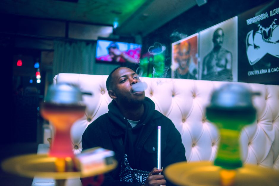 A young man enjoying a hookah session in a modern lounge setting with vibrant decor