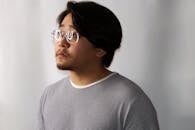 一个戴着眼镜、穿着条纹衬衫的体贴男人，在工作室里望向一边