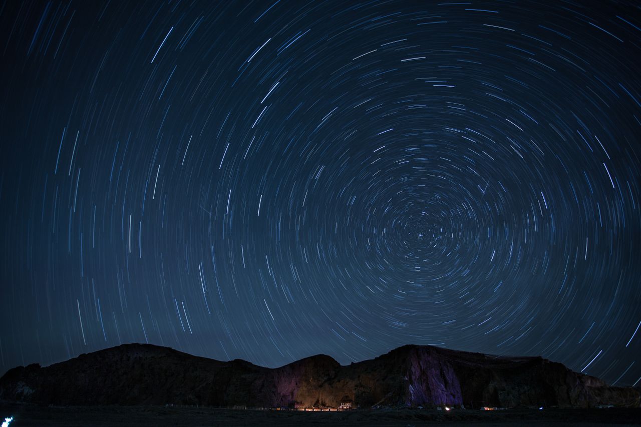 a mesmerizing night sky showcasing rotating star trails over a mountai