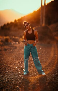 Young woman in casual attire poses confidently outdoors in Tehran during sunset.