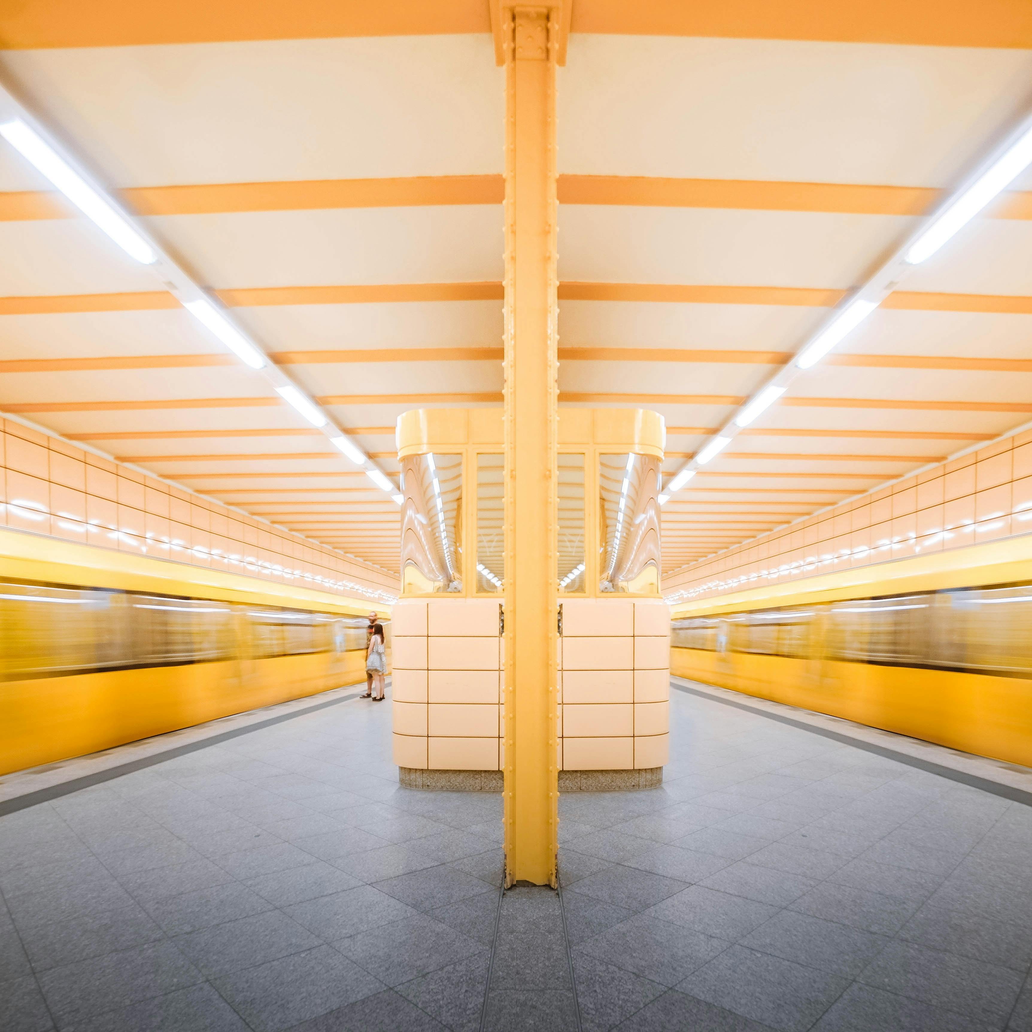 A dynamic view of Berlin's yellow subway station with motion blur capturing trains in transit.