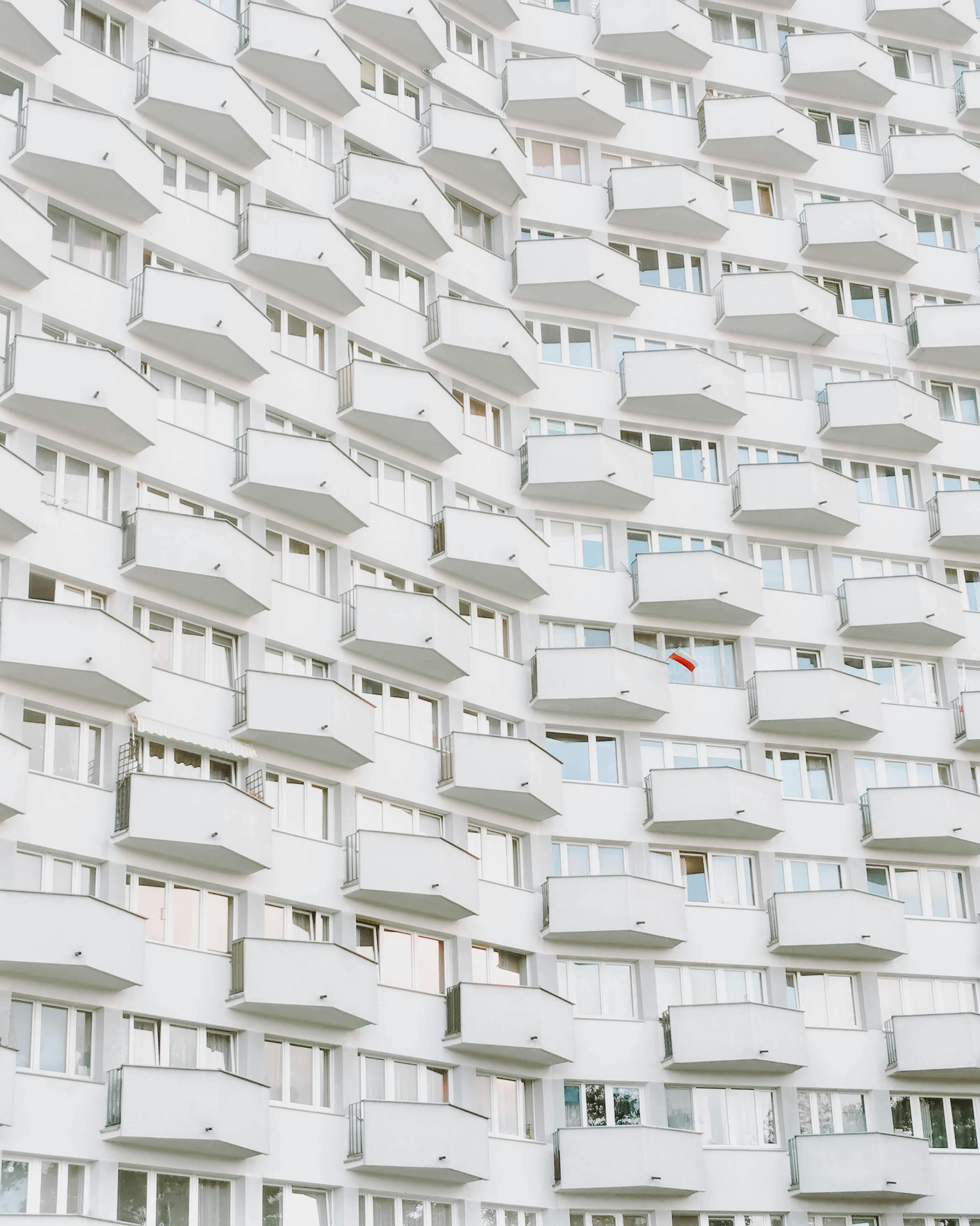 A striking view of a white apartment building in Warsaw, showcasing its repetitive balconies and windows.