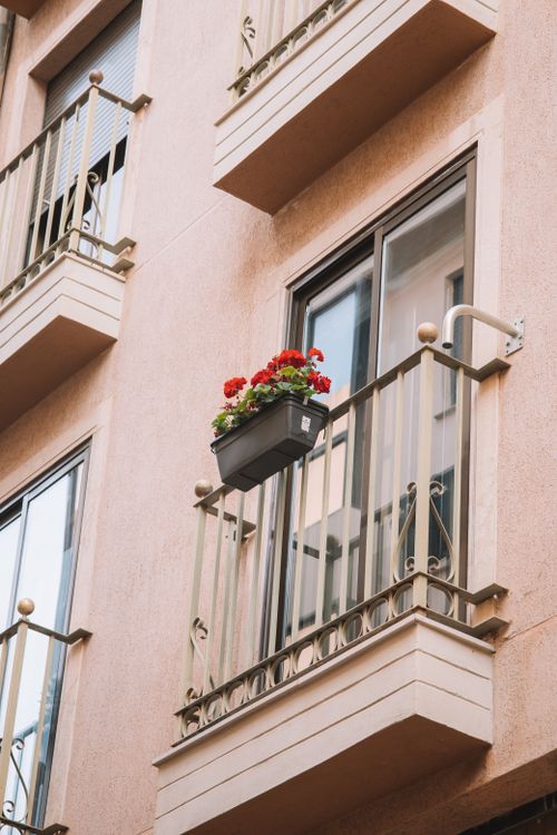 Free Close-up of a balcony with red flowers in Valencia, Spain, showing urban architecture and floral decor. Stock Photo