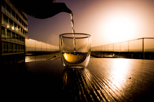 Free Man Filling Glass with Drink During Sunset  Stock Photo