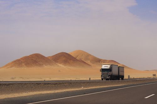 Free A truck travels along a desert road with rolling hills near Huarmey, Peru. Stock Photo