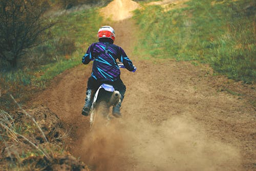 Free Man Riding Motocross Dirt Bike on Dirt Road Stock Photo