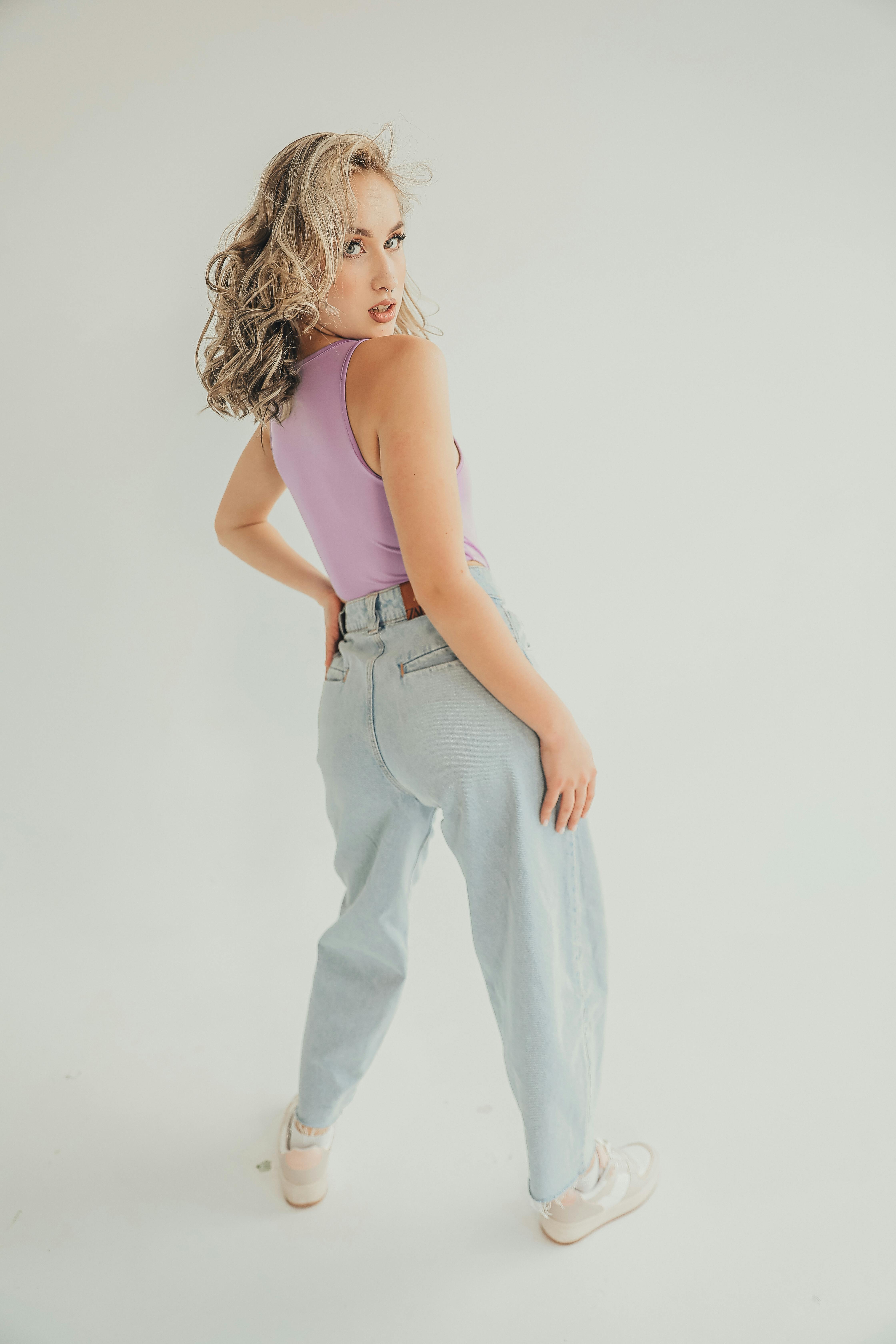 Free Fashionable woman in jeans and lavender top posing in a bright studio setting. Stock Photo