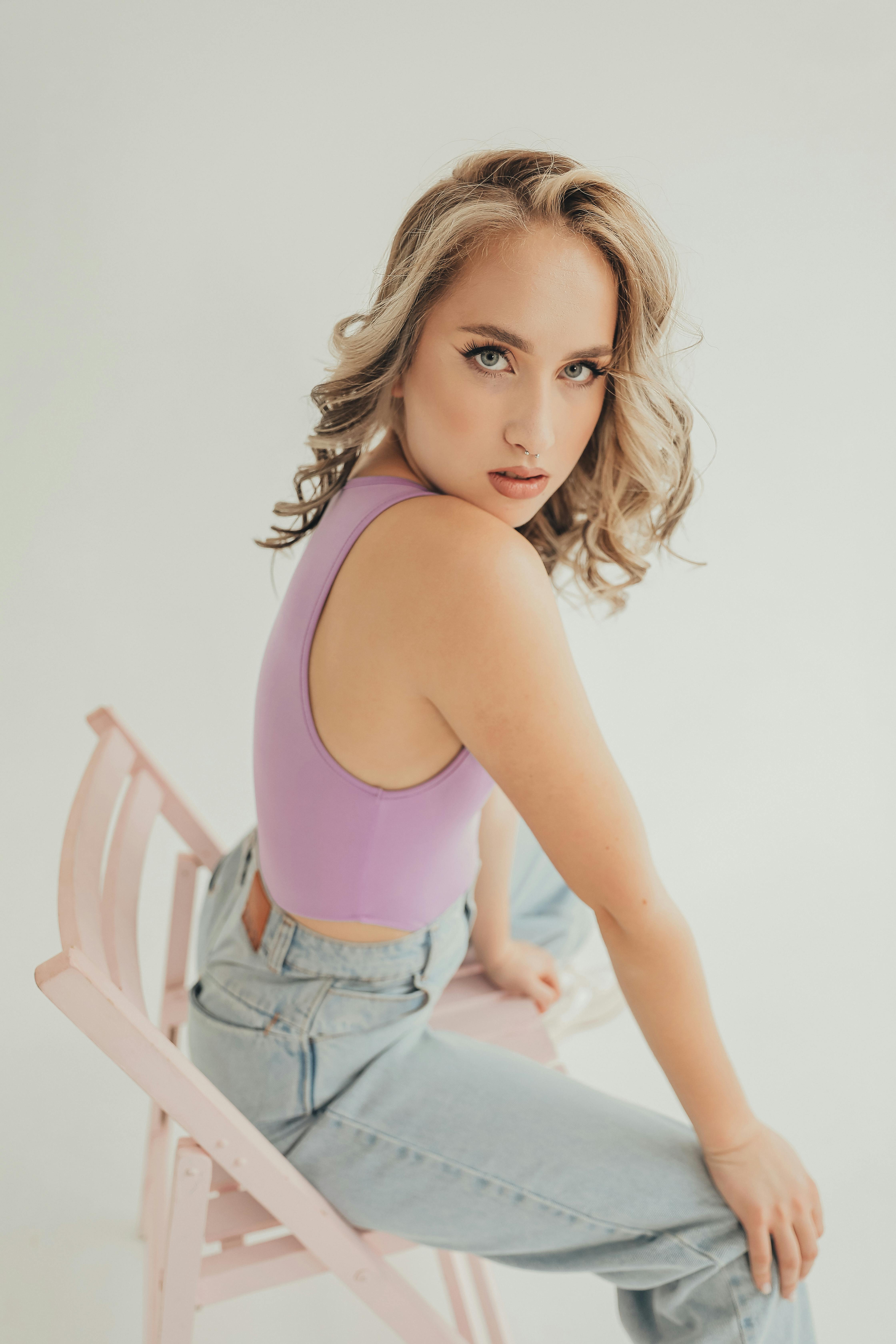Free Blonde woman in casual fashion, sitting in a relaxed pose on a white background. Stock Photo
