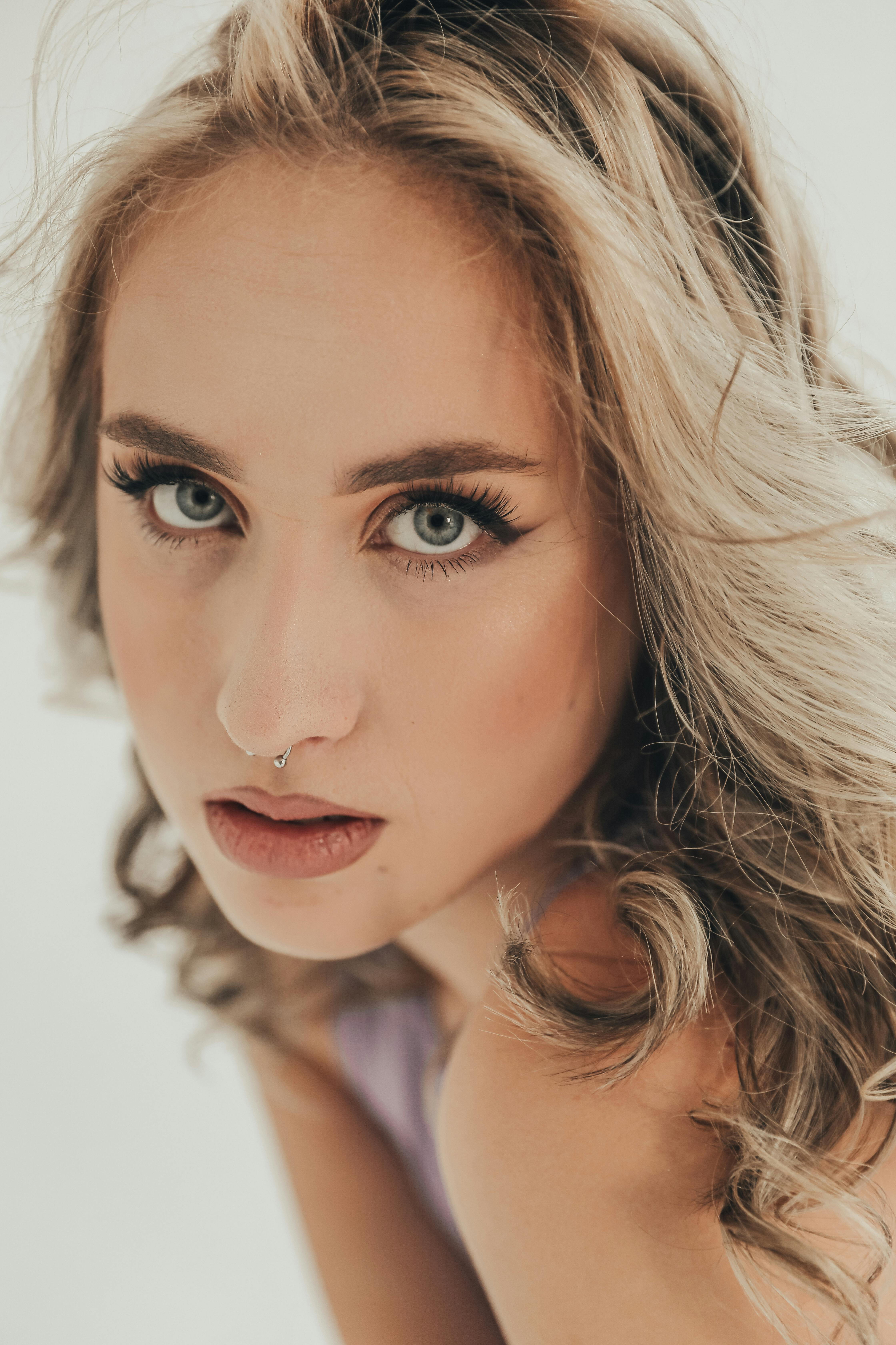 Free Close-up portrait of a blonde woman with captivating eyes posing in a studio. Stock Photo