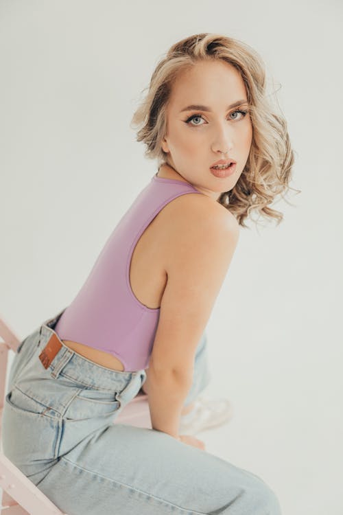 Young Woman in a Lilac Tank Top and Blue Jeans 