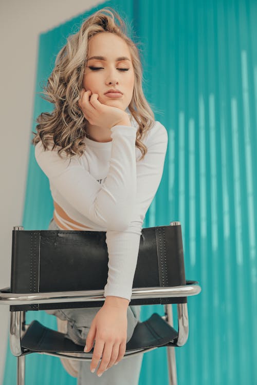 Blonde Woman Holding a Chair in a Studio 