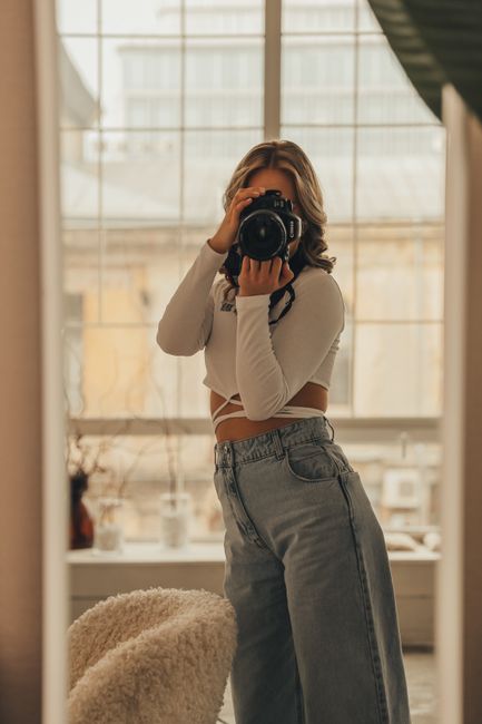 Elegant woman taking a photo with a DSLR in a modern room setting.