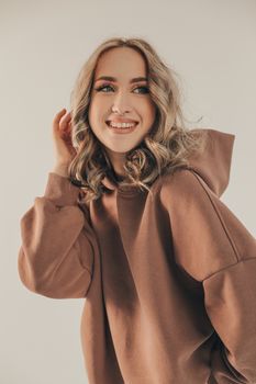 Portrait of a smiling woman in a cozy brown hoodie, posing confidently indoors.