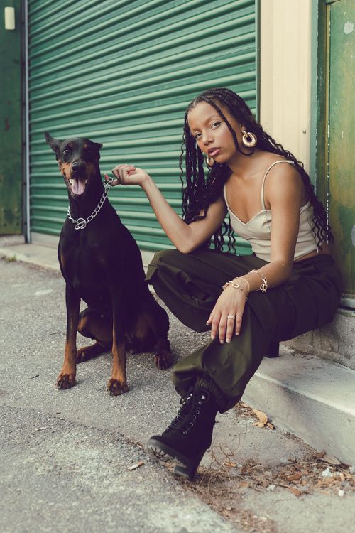 Free A fashionable woman with a Doberman dog poses on an urban street with green shutters. Stock Photo