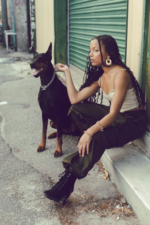 Free Fashionable woman sitting with Doberman on city street, exuding style and confidence. Stock Photo