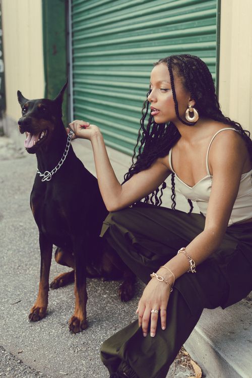 Free Woman with braided hair sitting beside a Doberman on city street. Stock Photo