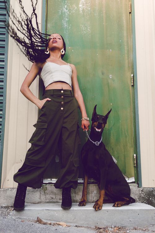 Free Fashionable woman with braided hair poses confidently with Doberman outside. Stock Photo