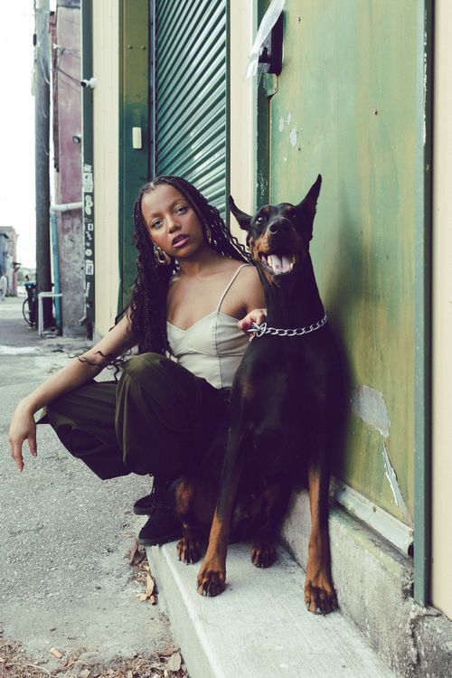 Free A woman poses with a Doberman on a city street, showcasing urban fashion style. Stock Photo
