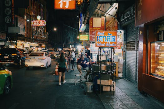 Bustling night street market scene with neon signs and urban life in an Asian city.