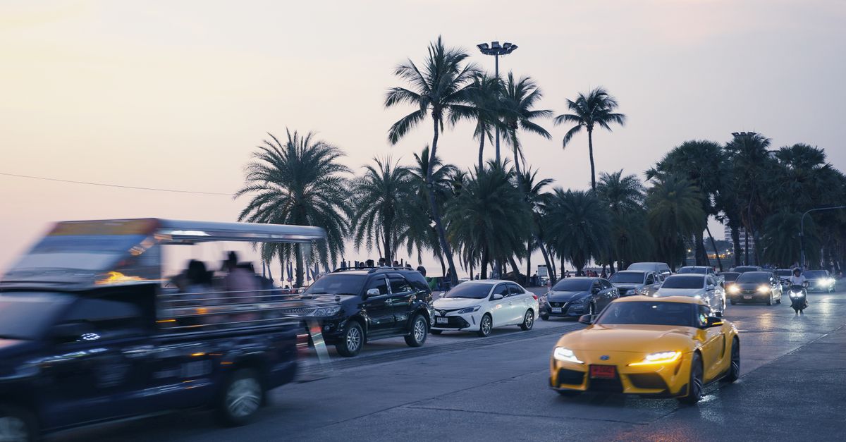 Photo by Tony Wu Busy city street at sunset with tropical palm trees and numerous vehicles in motion.