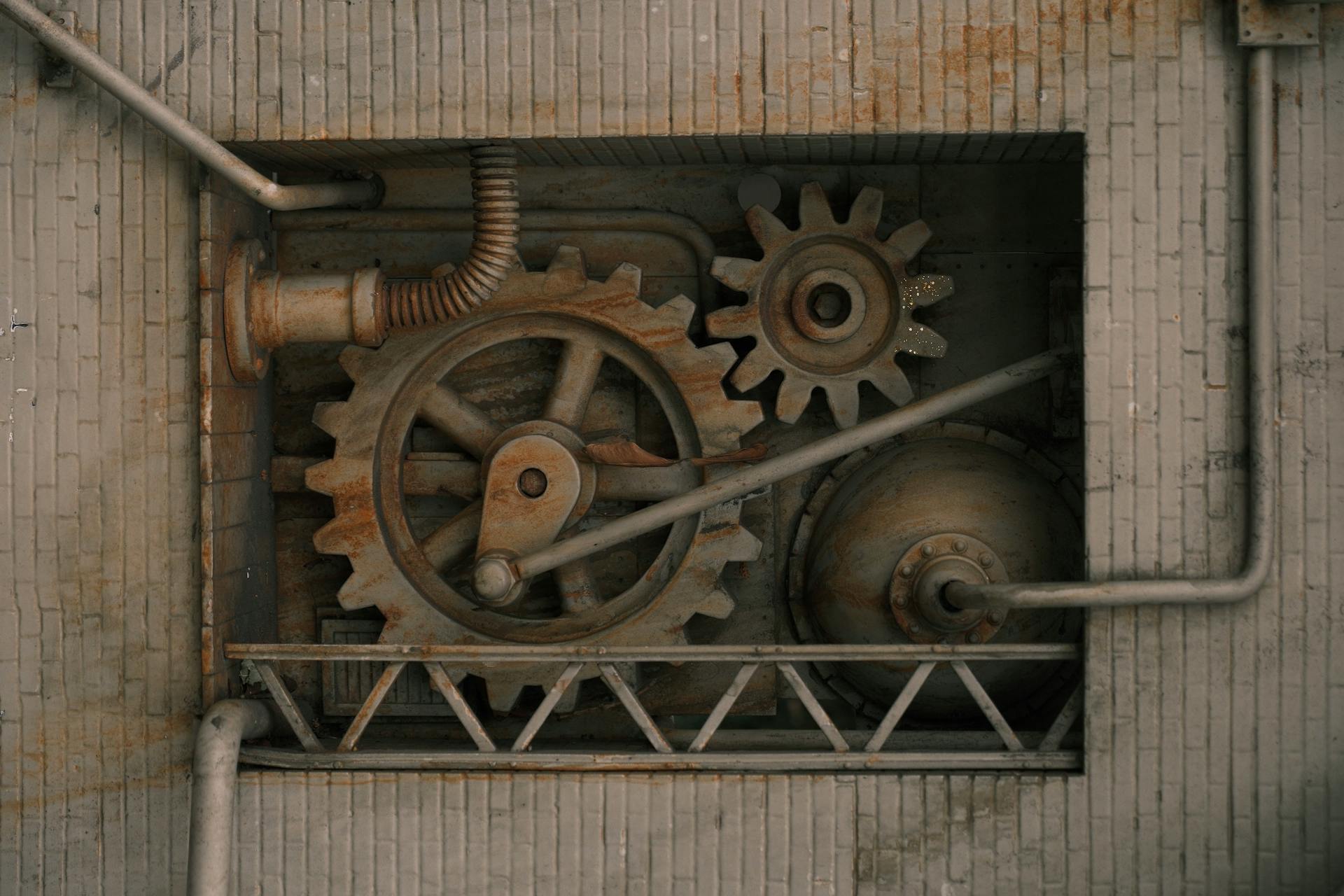 Detailed view of mechanical gears and pipes built into a brick wall, showcasing industrial design.