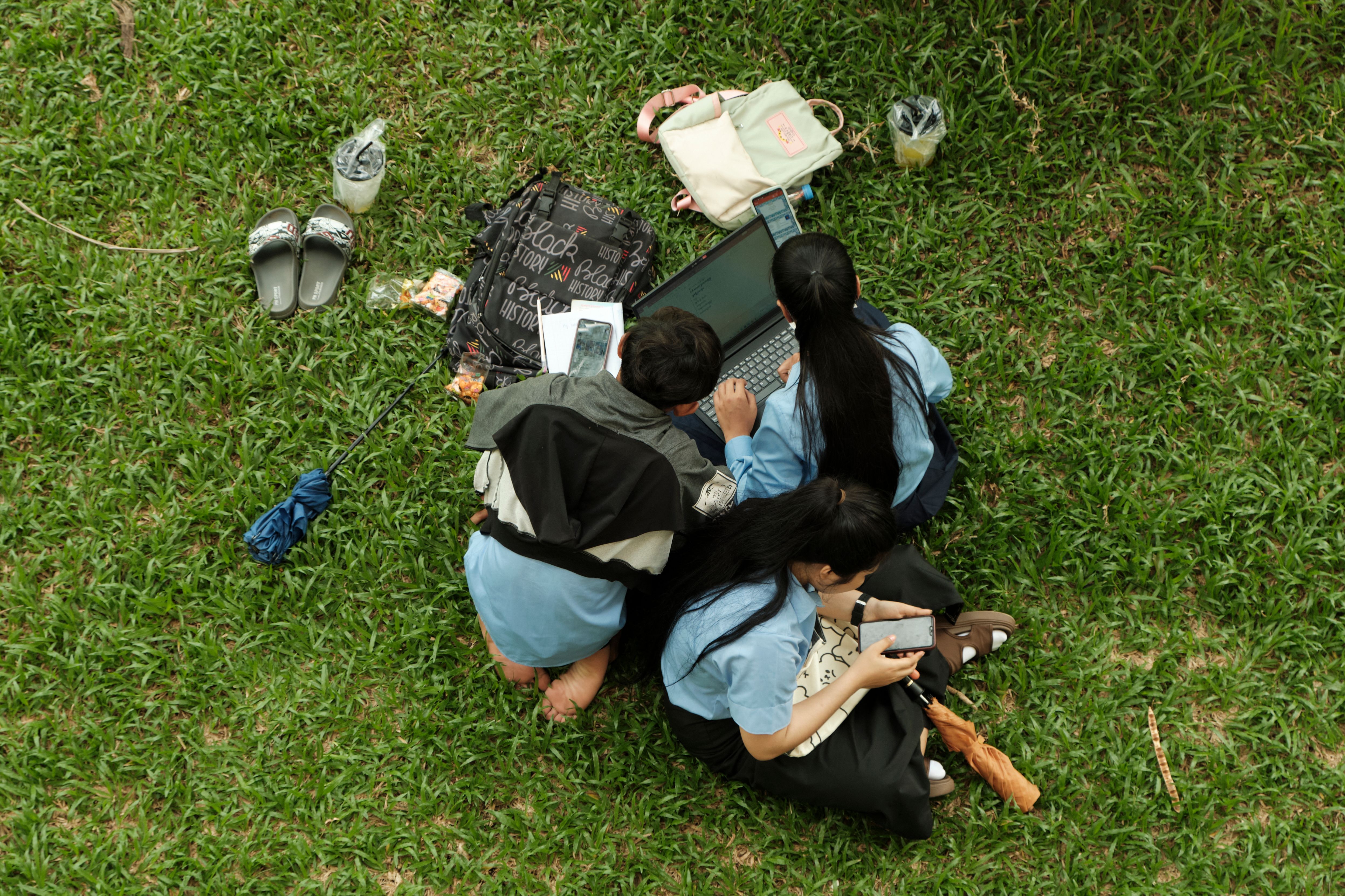 An international student using a laptop outdoors on a sunny campus