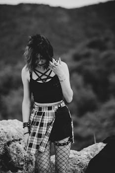 Stylish young woman in monochrome fashion with fishnet tights posing outdoors.