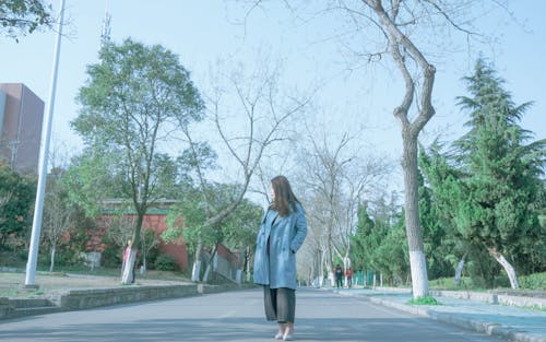 女人穿着蓝色外套站在沥青路面上
