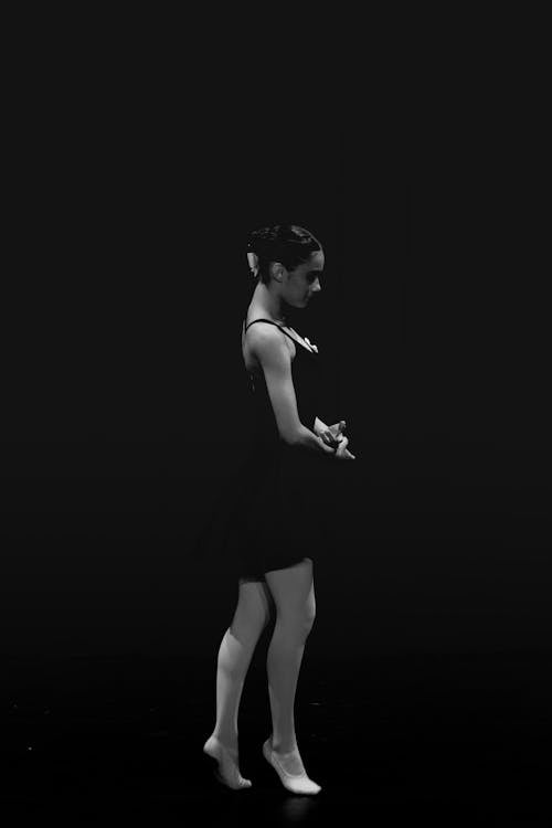 Woman Posing in Black Dress in Black and White on Black Background