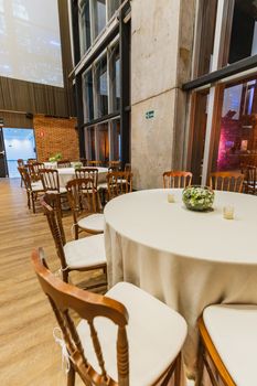 Interior view of a decorated restaurant with round tables and chairs set up for a celebration.
