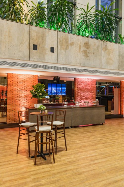Free Spacious restaurant interior featuring stylish chairs and tables, warm lighting, and lush green plants. Stock Photo