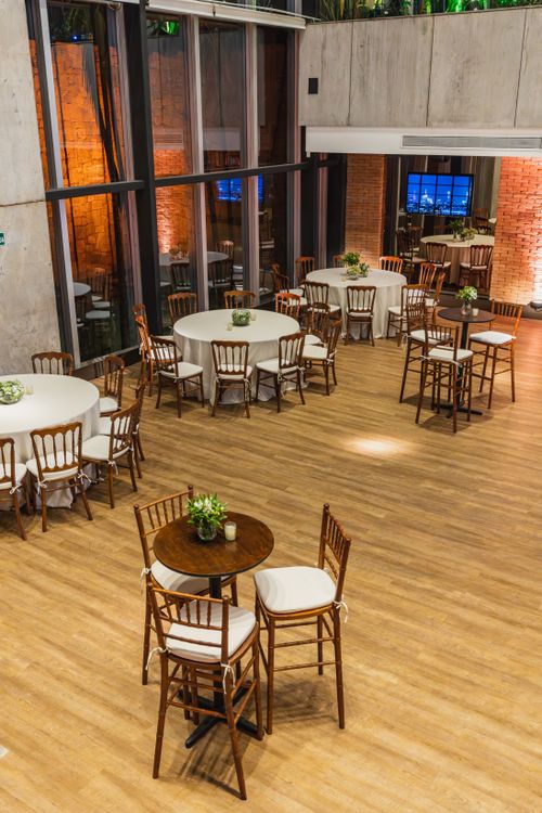Free High angle view of a beautifully decorated indoor event venue with round tables, wooden chairs, and floral centerpieces. Stock Photo