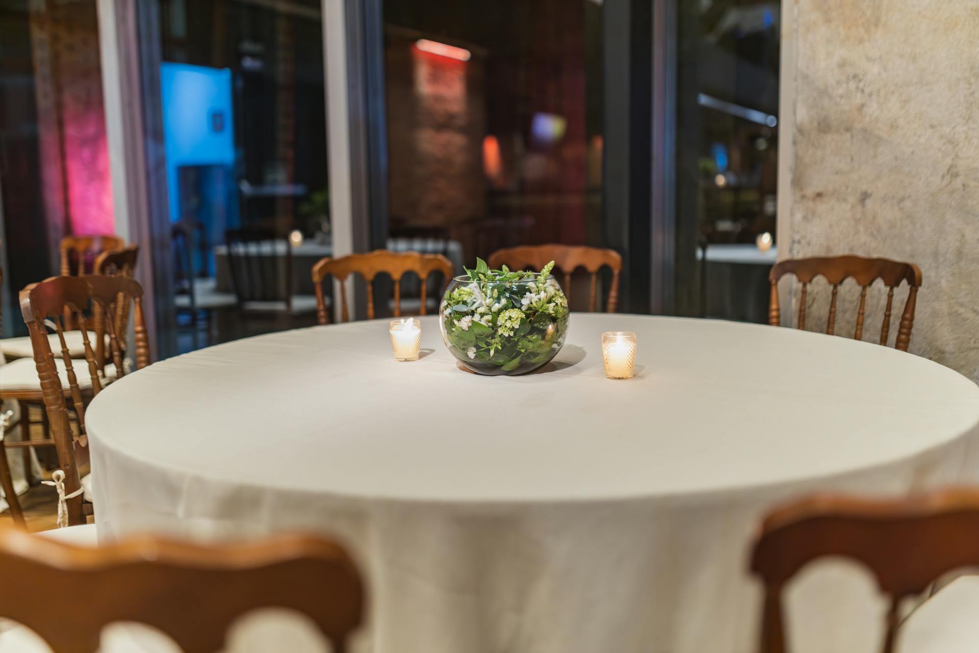 An elegant empty round table with floral centerpiece and candles in a cozy restaurant setting.