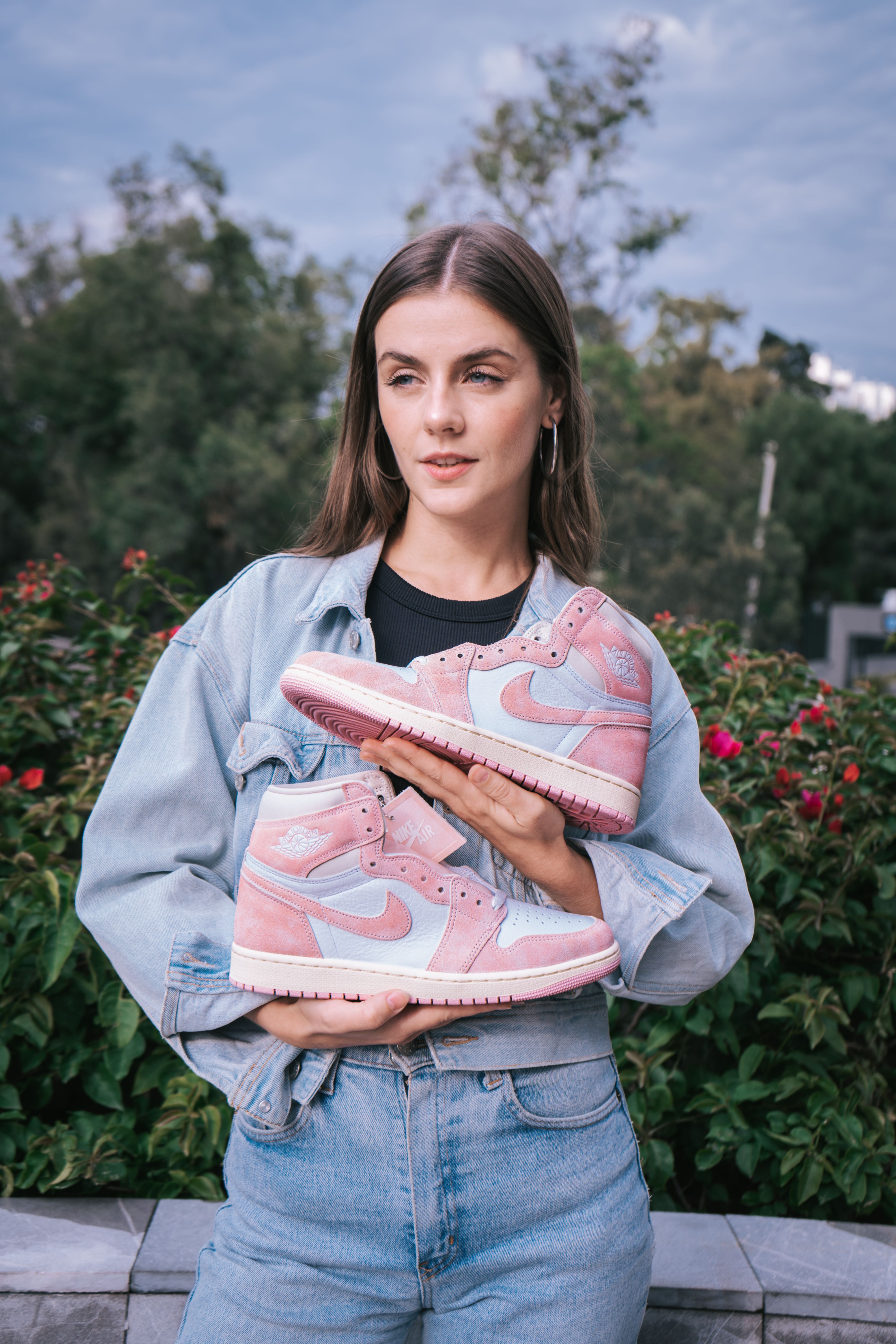 Young woman outdoors showing pink sneakers. Denim fashion look.