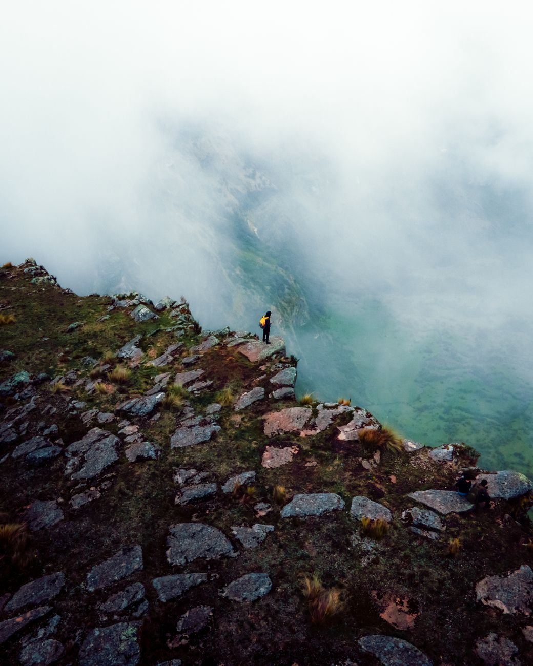 A lone hiker stands atop a fog-shrouded mountain in Ayacucho, Peru, offering a mystical view.