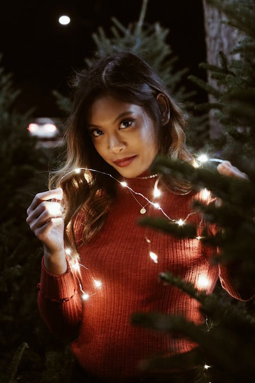 Woman Wearing Red Sweater Holding String Lights