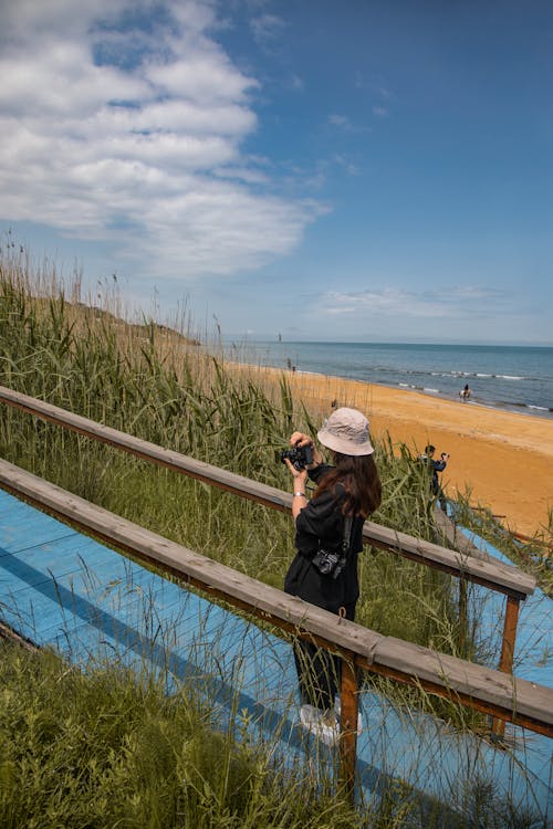 Free Woman Taking Pictures of a Trail near the Beach  Stock Photo