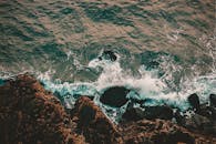 这张令人惊叹的空中镜头捕捉了海浪拍打岩石海岸线的画面，展现了大自然的原始之美