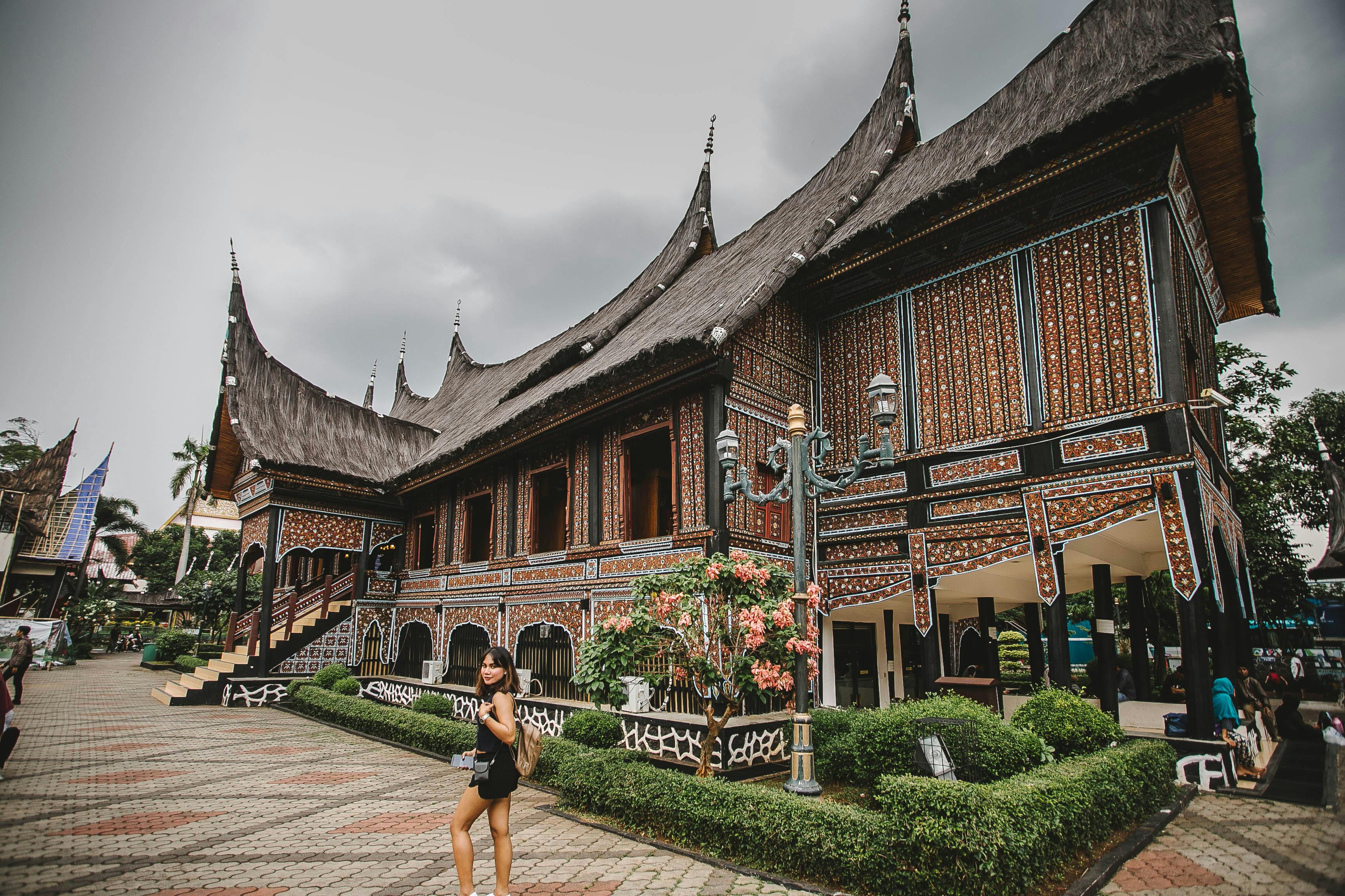 美丽的传统印尼建筑旁，有一个人在附近散步，建筑的细节清晰可见