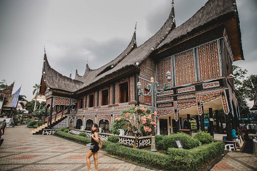 美丽的传统印尼建筑旁，有一个人在附近散步，建筑的细节清晰可见