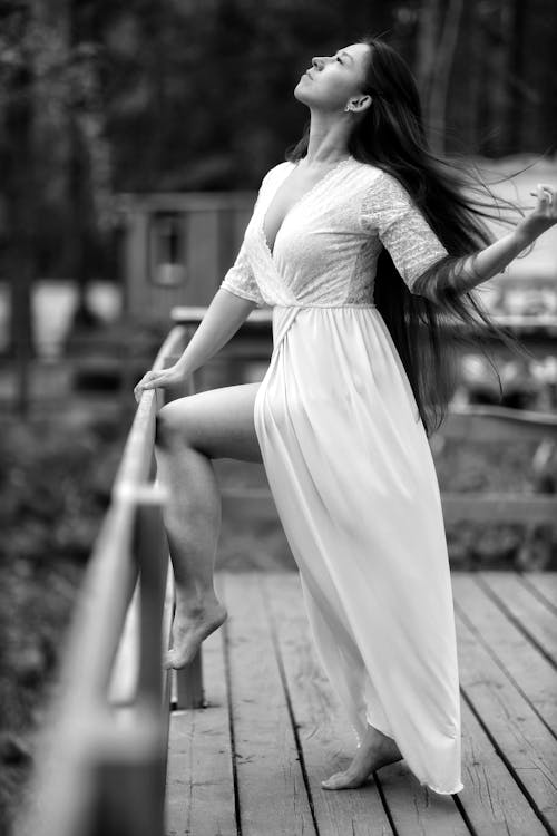 Young Woman in a Long White Dress Posing Outdoors 