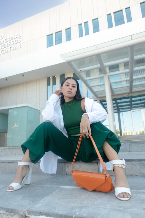 Young Fashionable Woman Sitting in front of a Building in City 