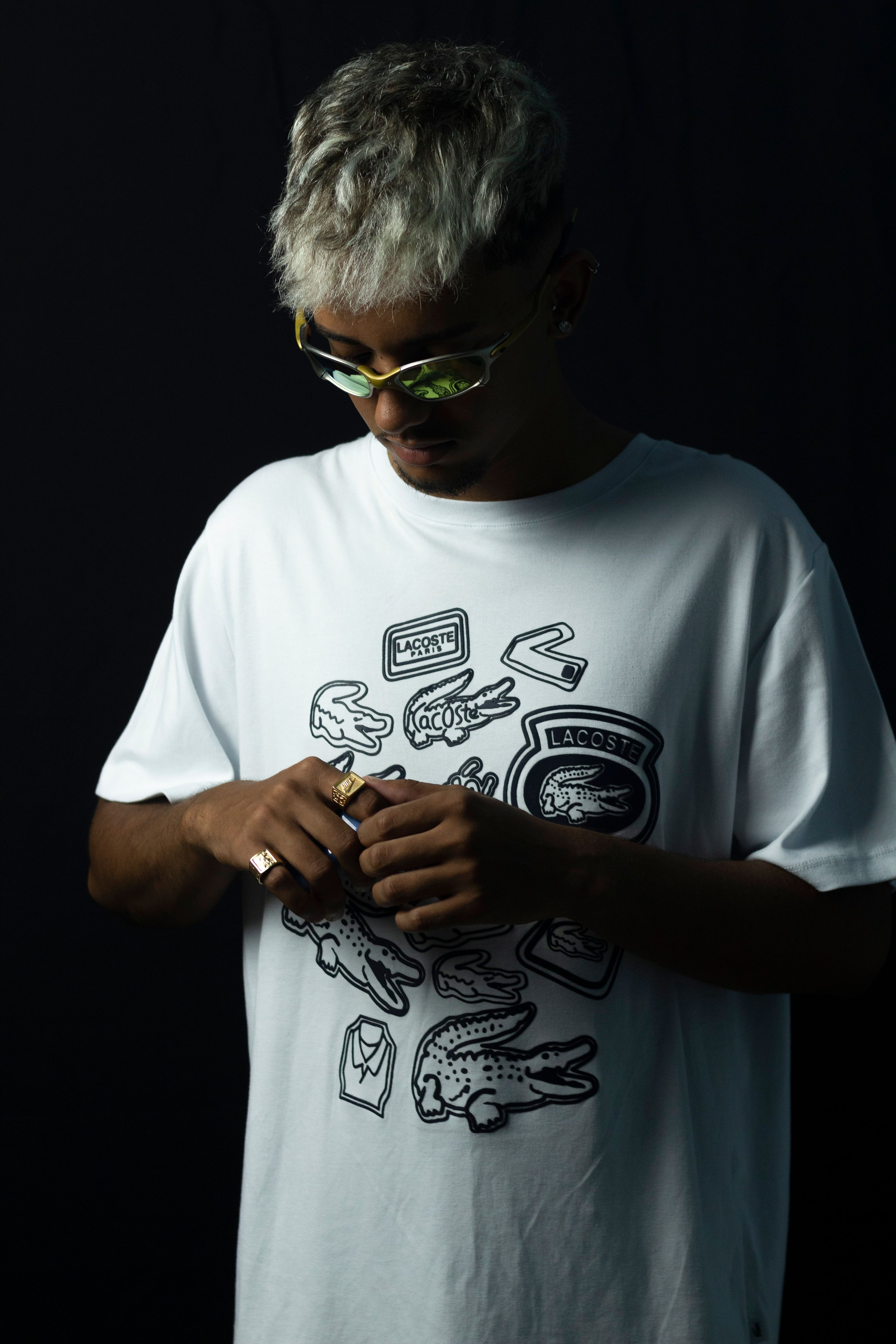 Portrait of a fashionable man with sunglasses and graphic t-shirt in a studio setting.