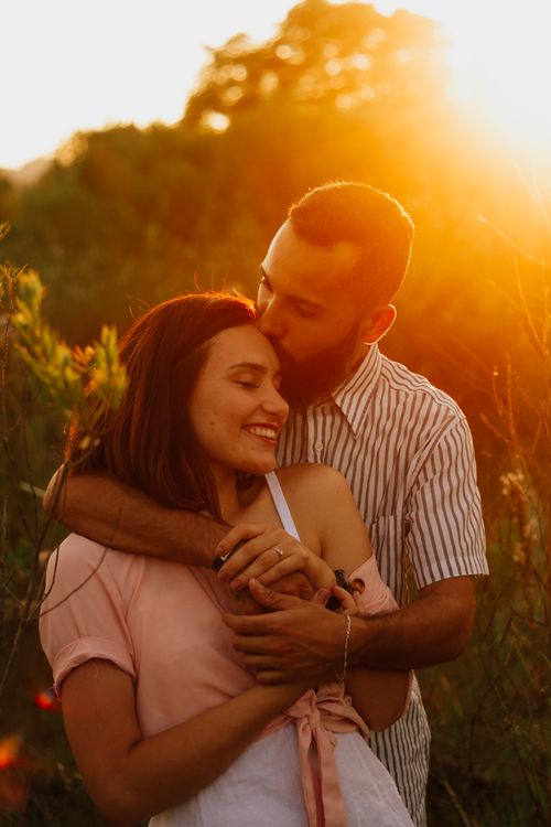 Free A couple shares a tender moment in a field at sunset, exuding love and warmth. Stock Photo