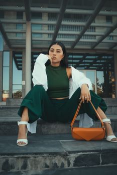 Confident woman posing fashionably in an urban setting on steps.