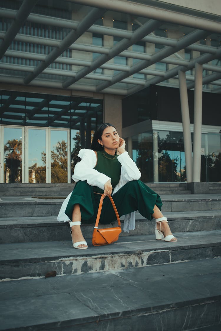 Young Fashionable Woman Sitting On Steps In City 