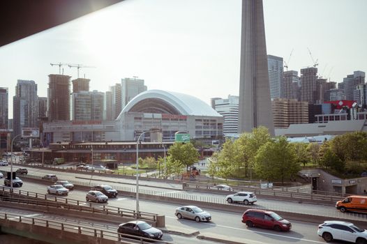 Daytime view of Toronto skyline with CN Tower and traffic on city streets, emphasizing urban life.