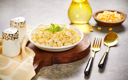 Free Delicious creamy corn macaroni garnished with herbs, styled with elegant cutlery for a rustic meal. Stock Photo