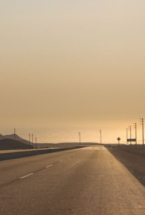 Free Serene view of a coastal highway during dusk, featuring the sea and an empty road in Paramonga, Peru. Stock Photo